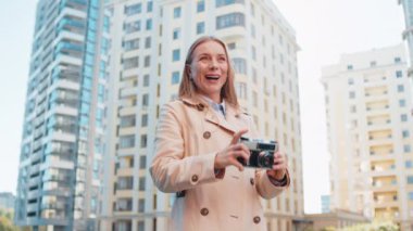 Hafta sonları şehir keşfi yapan orta yaşlı mutlu kadın turist dışarıda antika kameralarda fotoğraf çekiyor. Şehir sokağında tatilde uzun paltolu bir kız. Yaşam Tarzları.