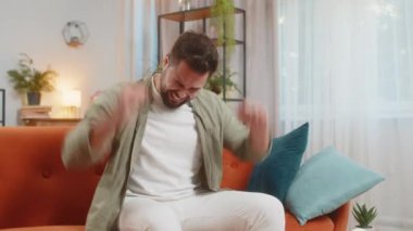 Üzgün genç adam umutsuzluk yalnızlık, sinir krizi, bağırış çağırış evdeki kanepede otururken. Kafkasyalı adam umutsuzluktan ağlıyor, haksız durum yüzünden üzgün..