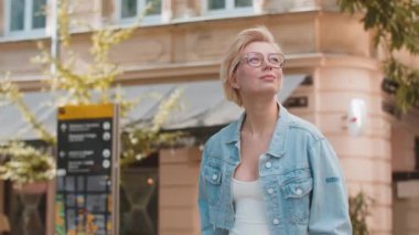 Beyaz kadın turist yaz günü açık havada şehir arka planında yürüyor. Sarışın kız gezgin şehir caddesinde yürümekten keyif alıyor. Kasaba yaşam tarzları.