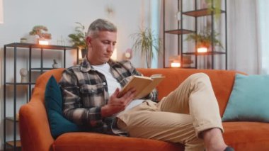 Beyaz adam ilginç kitaplar okuyor, sayfaları çevirip gülümsüyor edebiyattan zevk alıyor, rahat bir koltukta dinleniyor. Huzurlu, neşeli, genç bir adam. Oturma odasında kanepede dinleniyor.