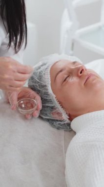 Kozmetik uzmanı, özel nemlendirici asit kokteyli uyguluyor. Kadının gözlerinin etrafına yüz derisi soyuluyor. Güzellik salonunda yüz bakımı yaşlanmayı önleyen kozmetik tedavi prosedürü. Kırışıklıklar gideriliyor