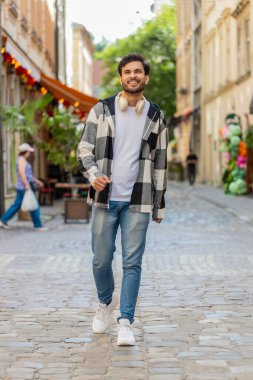 Mutlu Hintli turist yaz günlerinde şehir sokaklarında yürüyor. Genç gezgin gülümsüyor ve dışarıda eğleniyor. Kasaba yaşam tarzları, tatil, tatil gezileri.