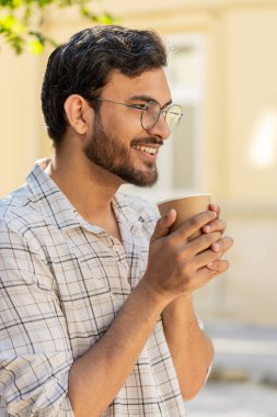Mutlu Hintli adam sabah kahvesinin tadını çıkarıyor sıcak içecek ve gülümsüyor. Dinleniyorum, ara veriyorum. Şehir merkezindeki caddede dikilen Latin kökenli genç adam kahve içiyor. Dışarıdaki kasaba yaşam tarzları.