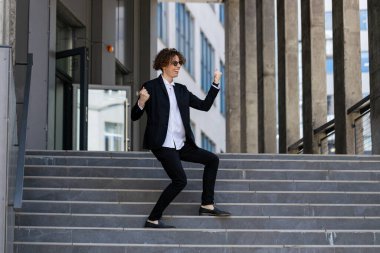 Dans, başarı ya da iş görüşmesi, terfi ya da kurumsal anlaşmadan sonra yürüyen adımlarla kutlama yapan iş adamı. Heyecanlı ya da mutlu dans çalışanı şehir merkezindeki satış hedeflerini ya da hedeflerini kutluyor.