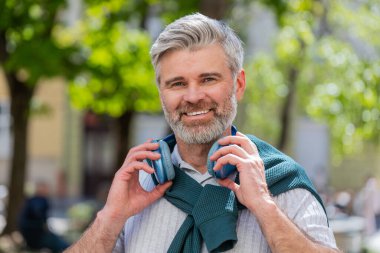 Neşeli, gevşemiş, olgun sakallı adam dışarıda dans eden enerjik disko rock n roll müziğini dinliyor. Yetişkin bir adam kablosuz kulaklıklarını çıkarıyor. Şehrin caddesinde gülümseyen kameraya bakıyor..