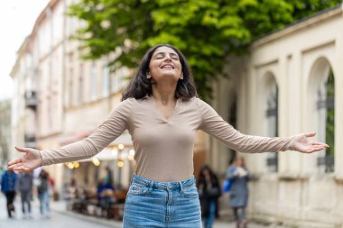 Hintli genç kadın derin bir nefes alıyor, dinleniyor, dinleniyor, meditasyon yapıyor, dışarıda sakinleşiyor. İspanyol kız şehir caddesinde mutlu günlerin tadını çıkarıyor. Kasaba yaşam tarzları