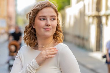 Mutlu, gülümseyen kızıl saçlı genç bir kadının portresi. Yandan bakan mutlu, mutlu bir yüz ifadesi. Rahatlama rüyası. Şehir sokağındaki kız. Kasaba yaşam tarzları.