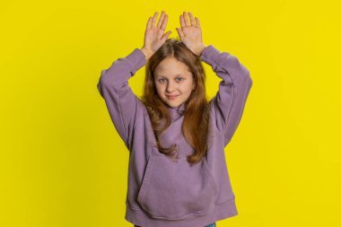 Ben küçük tavşanım. Sevimli, genç, sevimli, çocukluk çağındaki bir çocuk, güler yüzlü, tavşan kulağı hareketi yapıyor, eğleniyor, komik mizahi ruh haliyle dalga geçiyor. Sarı arka plandaki çocuklar