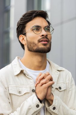 Hintli adam Tanrı 'ya kapalı gözlerle dua ediyor dışarıda kutsama, yardım ve af diliyor. Şehir merkezindeki caddede el ele tutuşup şans dileyen Arap Hindu. İş adamları yaşam tarzları. Dikey