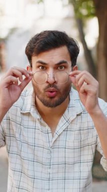 Aman Tanrım, vay canına. Hintli adam kameraya şaşkın bir şekilde bakıyor, büyük açık gözlerle, ayarlama gözlükleri ani zaferle şok olmuş, piyango hedefi başarısı, açık havada iyi haberler. Şehir sokağındaki adam. Dikey