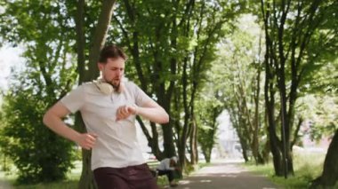 Şehir parkında koşan ve akıllı sineklere bakan mutlu koşucu. Heyecanlı adam spor takip cihazı kullanıyor ve başarıyı kutlayan sonuçları kontrol ediyor. Sporcu çocuk antrenman sonuçlarından memnun..