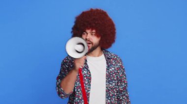 Kafkasyalı genç adam megafonla konuşuyor, haberleri duyuruyor, reklam indirimlerini yüksek sesle duyuruyor, hoparlörü kullanarak konuşma yapıyor. Stüdyonun mavi arka planında izole edilmiş mutlu stil adamı.