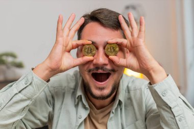 Serbest çalışan genç bir borsa simsarı sanal paraların BTC tarafından izlendiğini gösteriyor. Zenginliğin finansal refahı artıyor. Ofis masasında dizüstü bilgisayarı olan adam..