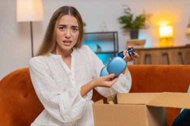 Memnun olmayan bayan müşteri karton kutu açıyor. Kablosuz kulaklıklar zarar görüyor. Genç bir kadın eve kötü sipariş teslimatıyla ilgili şikâyette bulunmakta zorlanıyor. Yaşam biçimi