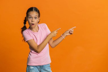 Ergenlik çağındaki kız çocuğu boş bir yeri işaret ediyor. Ticari indirimli mesajlar için reklam alanı, ürün tanıtımı için fotokopi alanı. Turuncu arka planda ergen çocuklar