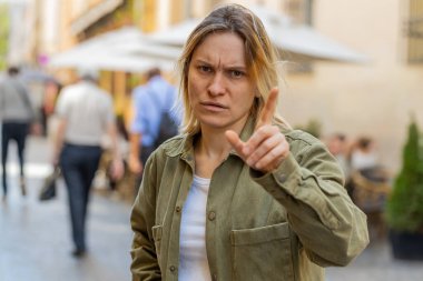 Tatsız, berbat bir fikre tepki veren, kötü kalite kafa sallamaktan memnun olmayan bir kadın. Hayır, teklifi reddet, dışarıda evlenme teklifini sevme. Beyaz kız turist şehir caddesinde duruyor.