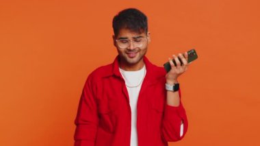 Hintli ilgisiz Hintli adam, akıllı telefonda can sıkıcı konuşmalar yapıyor. Arap genç adam arkadaşlarıyla cep telefonu konuşmaktan yorgun düşmüş turuncu arka planda internet sohbeti yapıyormuş.