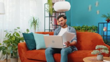 Stresli Hintli adam, ev odasında dizüstü bilgisayarla çalışıp ödenmemiş banka borçlarına bakıyor evrak işleri planlama bütçesi, mortgage ödemelerini hesaplıyor. Memnuniyetsiz adam kağıt faturaları başınızın üstüne atıyor.