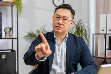 Bilgisayarda çalışan Asyalı orta yaşlı iş adamı el sıkışıyor ve 