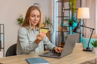 Banka kredi kartı ve dizüstü bilgisayarını merkez ofisteki online alışveriş ödemeleri için kullanan Kafkasyalı mutlu bir serbest kadın. İş anlaşması. E-bankacılık uygulaması ile gülümseyen kız alışverişi.