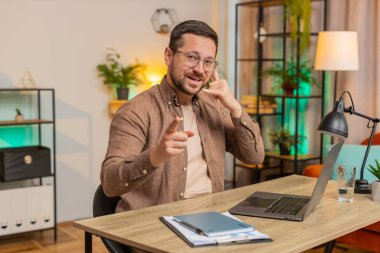 Beni ararsın. Genç Kafkasyalı patron iş adamı dizüstü bilgisayarını kullanarak telefon görüşmesi yapmak istiyor, bana işaret veriyor, online randevu. Ofisteki serbest çalışan adam oturma odasındaki kameraya bakıyor..