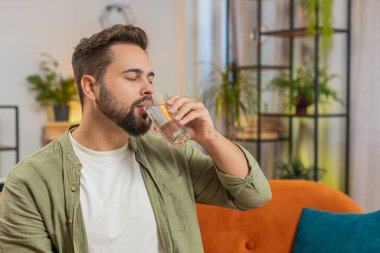 Tatmin olmuş beyaz tenli bir adam evinde, kanepede oturup sağlıklı bir hayat sürüyor, bir bardak saf su içiyor, gülümsüyor. Her gün su iç. Odadaki adam kameraya gülümsüyor..