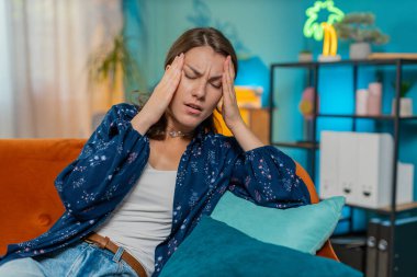 Hasta, beyaz bir kadın baş ağrısı, tansiyon, migren, stres, ekşitme, yüksek tansiyon gibi sorunları tedavi etmek için tapınakları ovuyor. Yetişkin bir kız odada kanepede yatıyor..