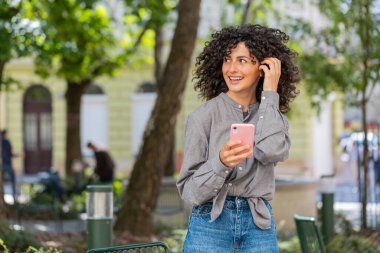 Kafkasyalı genç bir kadın sosyal medya uygulamasında akıllı telefon kullanarak kısa mesajlar yazıyor, internette sörf yapıyor, dinleniyor, dışarıda mola veriyor. Şehir caddesinde duran bayan kız. Güneşli park