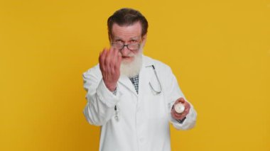 İyileşme zamanın geldi. Kıdemli yaşlı doktor kardiyolog cep saati zamanı gösteriyor. Başparmağını kameraya doğru çevir. Sarı arka planda eczacı dedesi.