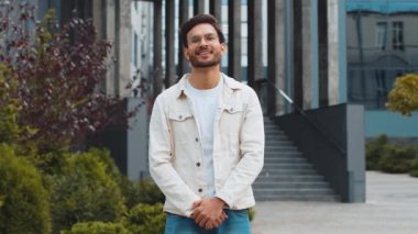 Mutlu Hintli genç bir adamın portresi güler yüzlü, kameraya bakan mutlu yüz hayal kuran, dinlenen rahatlayan, dışarıda iyi haberler veren. Şehirdeki Arap Hindu adam. İş adamları