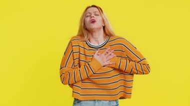 Stresli, korkmuş, beyaz tenli genç bir kadın kalp krizi geçirme riski ve kalp krizi geçirerek ağır hastalık belirtileri gösteriyor. Sarı arka planda izole edilmiş yetişkin bir kız.