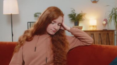 Evdeki oturma odasındaki kanepede oturan, gündelik elbiseli, yalnız, yalnız, genç bir kadın sorunları düşünüyor. Sıkılmış kadın kız, daireye bakarken kendini kötü hissediyor..