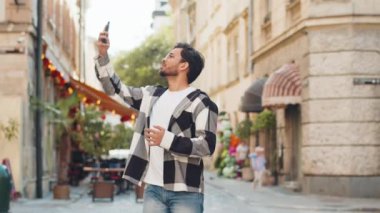 Gündelik gözlüklü genç bir turist akıllı telefondan iletişim sinyali ve internet yakalamaya çalışıyor. Şehir caddesinde daha iyi bir bağlantı için telefonu kaldırdı. Hüsrana uğramış Hintli adam kasabada..