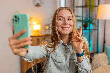 Beyaz, orta yaşlı, serbest çalışan bir kadın sosyal medya için akıllı telefon kullanıyordu. Masada oturmuş gülümsüyormuş gibi davranıyordu. Kız kıza çalışma, e-öğrenme, internetten uzak çalışma..