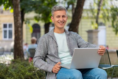 Mutlu olgun bir adam, şehir caddesinde bir sandalyede otururken dizüstü bilgisayarı açar. Beyaz saçlı beyaz adam defter üzerinde çalışıyor, mesajlar gönderiyor, internetten alışveriş yapıyor, film izliyor. Kasaba yaşam tarzları.