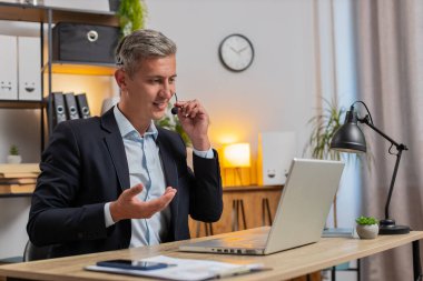 Kulaklık takmış yakışıklı, beyaz, genç bir işadamı bilgisayarla ofis masasında konuşuyor. Erkek danışmanın internet danışmanlığı, müşteri desteği, şikayetleri olan müşterilere yardım.