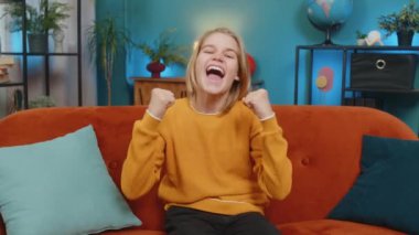 Beyaz çocuk, evdeki koltukta görevini tamamladıktan sonra heyecan gösteriyor. Zaferi kutladığımı haykırarak en sevilen spor takımına tezahürat yapan ve neşe saçan TV izlerken