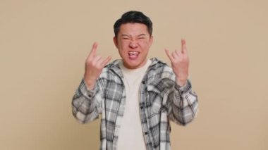 Coşkulu, mutlu, orta yaşlı, Asyalı, rock 'n roll jesti yapan, çılgın bir ifadeyle evet diye bağıran, çılgın, dans eden, sevinçli, zafer kazanan bir adam. Bej arka planda olgun Çinli bir adam.