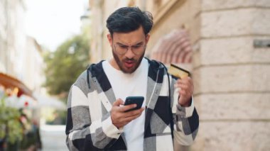 Hintli adam internet üzerinden alışveriş yapmaya çalışırken kredi kartını bloke etmiş. Sokaktaki kızgın genç Arap turist, banka alım satımı reddediyor, ödeme dengesizliği yaşıyor..