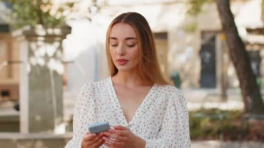 Akıllı telefon daktilosu kullanan genç bir kadın aniden piyango şokunu kaybeder. Kötü haber kaybı uygulaması başarısız virüs hırsızlığı. Kentsel sokakta giyinmiş üzgün bir turist kız..