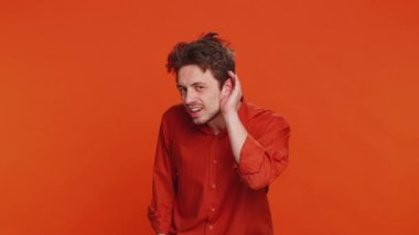 - Seni duyamıyorum. - Ne? Kafkasyalı bir adam senin şaşırmış ve kaşlarını çatmış bir şekilde daha yüksek sesle tekrar etmek, bilgi almak ve sağır olmak için kolunu kulağının dibinde tutmaya çalışıyor. Turuncu arka plandaki genç adam.