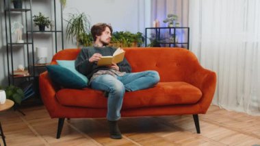 Kafkasyalı genç adam ilginç kitaplar okuyor, sayfalarca gülümsüyor edebiyattan zevk alıyor, rahat bir koltukta dinleniyor. Huzurlu, neşeli adamın portresi. Oturma odasında dinleniyor.