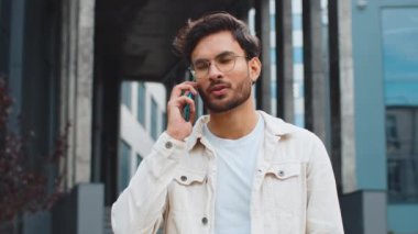 Telefon, iyi haber, dedikodu. Akıllı telefondan hoş sohbetler yapan mutlu Hintli adam dışarıda arkadaşlarıyla konuşmaktan zevk alıyor. Şehir caddesinde duran Arap Hindu adam. Kasaba yaşam tarzları