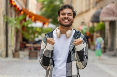Heyecanlı mutlu gezgin bağırıyor, başarıyı kutluyor, kazanıyor, gol başarısı, iyi haber, piyango talihi, açık havada zafer. Şehir caddesinde dikilen genç bir İspanyol. Yaşam Tarzları.
