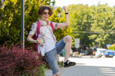 Heyecanlı mutlu gezgin bağırıyor, başarıyı kutluyor, kazanıyor, gol başarısı, iyi haber, piyango talihi, açık havada zafer. Şehir Güneşi Sokağı 'nda yürüyen genç bir adam. Yaşam Tarzları.