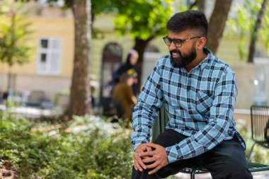 Hasta Hintli sakallı adam acı veren bir rahatsızlıktan muzdarip diz eklem ağrısı, bacak kasları, dışarıda yürüyemiyordu. İspanyol, üzgün, dizlerine masaj yapan hasta adam. Şehir sokaklarında romatizma krampı geçiriyor.