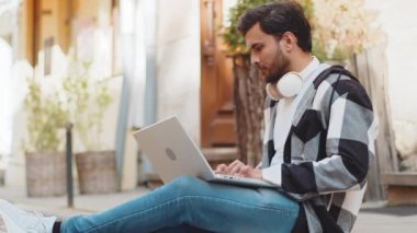 Hintli serbest çalışan bir adam dizüstü bilgisayarını kullanarak sokakta oturuyor teneffüste internet üzerinden iş arama sitesinde sohbet ediyor. Genç adam netbook ekranına bakıyor, daktilo şehir içinde mesajlar gönderiyor