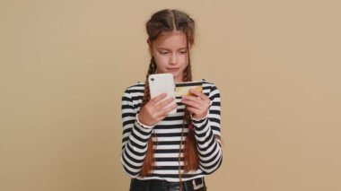 Çocuk yaşta kredi kartı ve akıllı telefon kullanan mutlu bir çocuk. Harcama parasını transfer ediyor, online alışveriş yapıyor, yemek siparişi veriyor. Bej arka planda izole edilmiş küçük çocuklar
