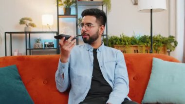 Neşeli Hintli adam gezici hoparlörlerden hoşlanıyor dedikodular, dedikodular, iyi haberler koltukta oturuyor. Modern ev odasındaki arkadaşlarıyla telefon konuşması yapan mutlu, heyecanlı Arap adam..