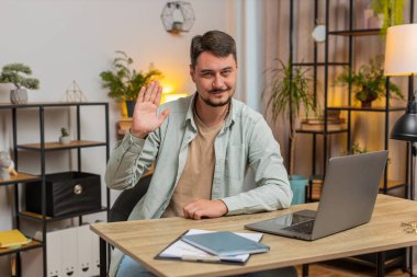 Hoş geldiniz. Kafkasyalı serbest çalışan mutlu adam el sallayarak selam veriyor. Birine hoş geldin diyor. İnternet ağları, uzak mesafe sohbetleri. Ofiste dizüstü bilgisayarla masada oturan serbest çalışan bir adam..